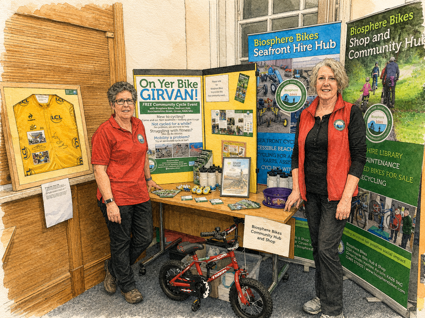 Two members of the Biosphere Bikes team at a community event stand with information banners and a small red bike