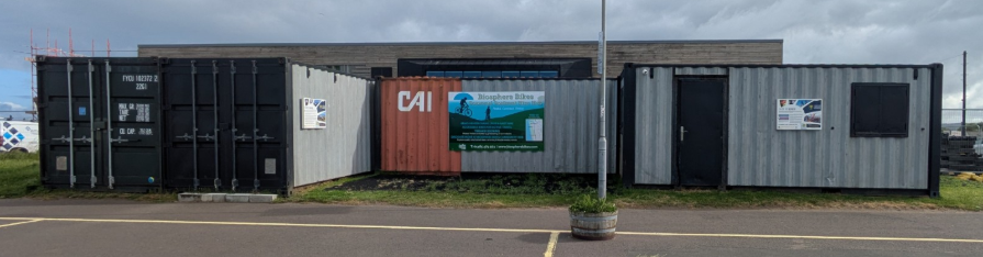 The current container hub on Girvan seafront — mixed containers and signage.